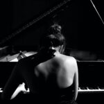 fotografia com foco seletivo de uma mulher a tocar piano de cauda
