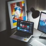 turned on MacBook on table beside iMac