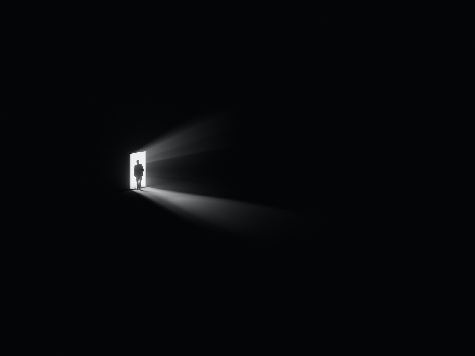 a person standing in a doorway with a light coming through it