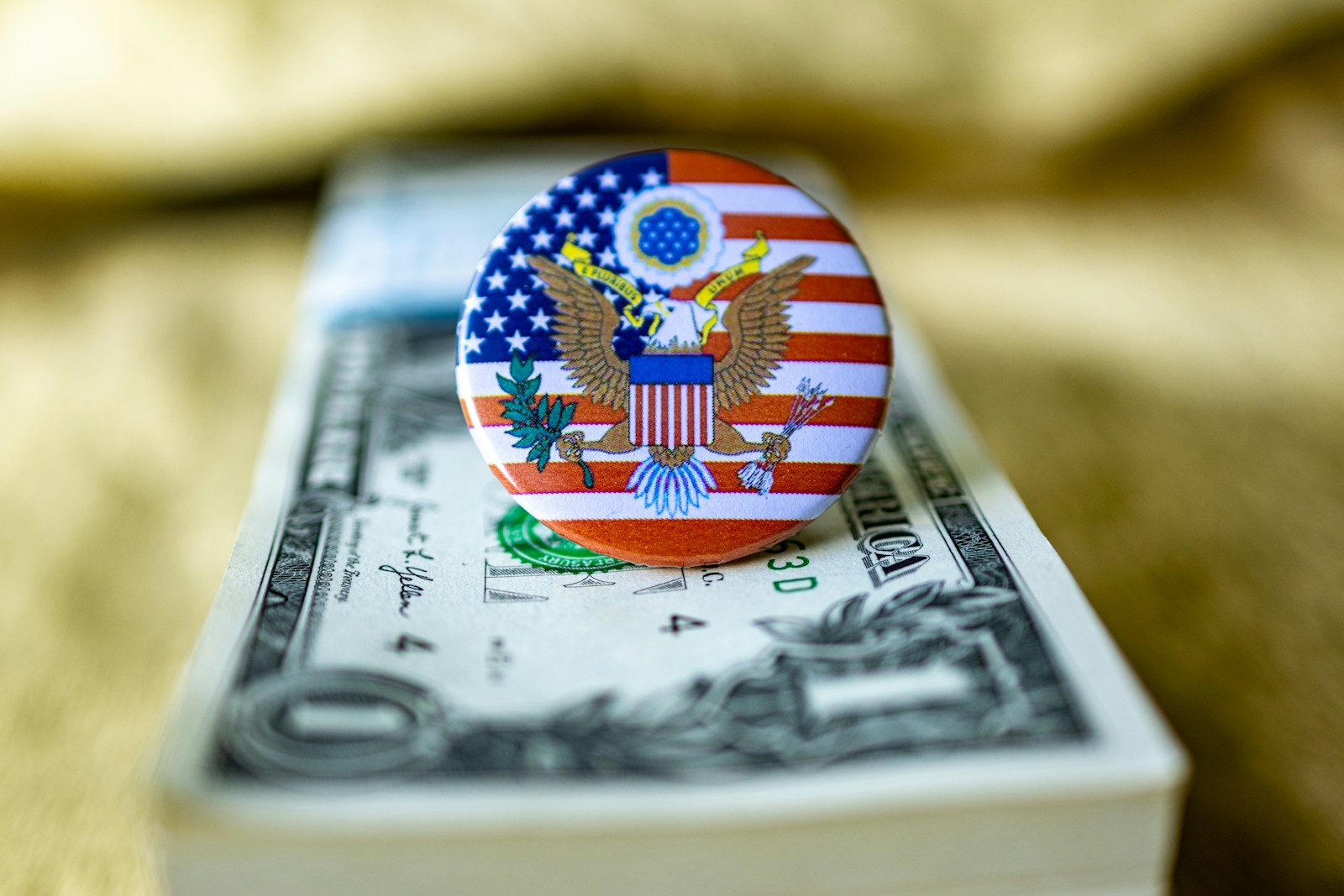 An american flag pin sitting on top of a one dollar bill