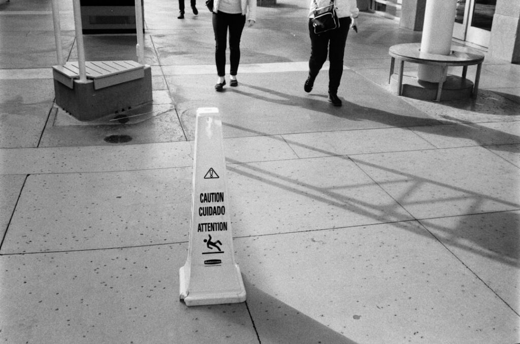 Wet floor caution sign on sidewalk with people walking