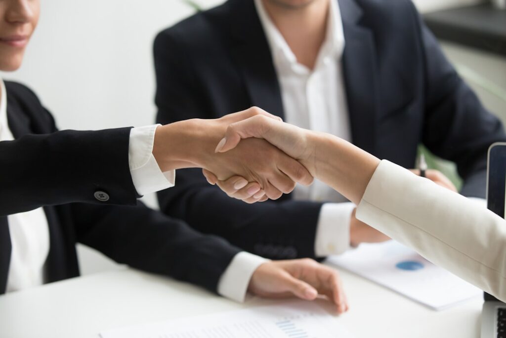 Two people shaking hands in front of laptop — insurance negotiation strategy