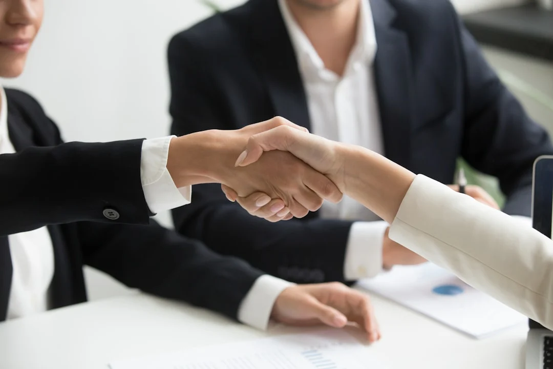 Two people shaking hands in front of laptop — insurance negotiation strategy