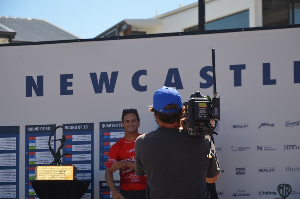 Woman posing for camera in front of newcastle sign