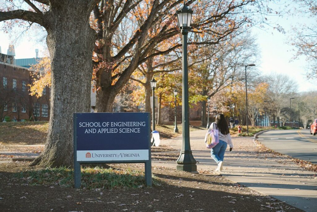 A student walks past a sign for school of engineering